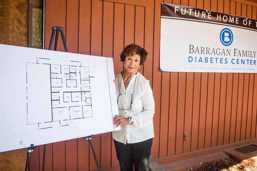 A lady posing beside a building plan